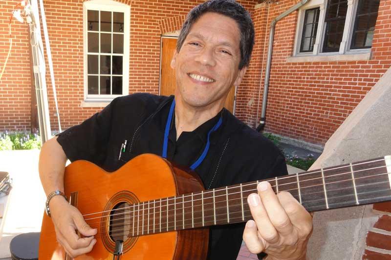 Frank playing his guitar and smiling